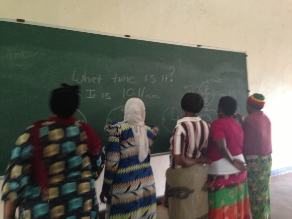 The women draw clocks to practice asking each other "What time is it?". 